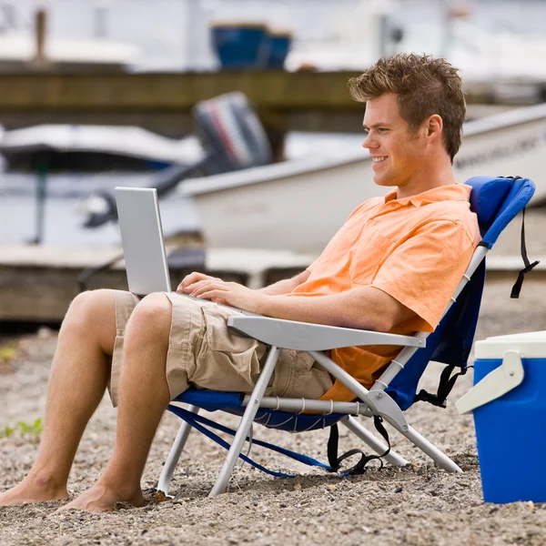 Человек с ноутбуком на пляже — стоковое фото