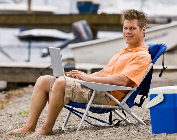 Человек с ноутбуком на пляже — стоковое фото