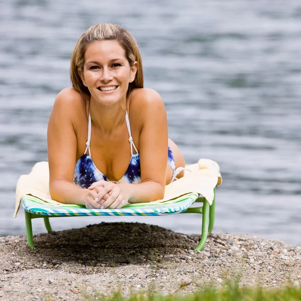 Kvinde æglæggende på lounge stol på stranden - Stock-foto