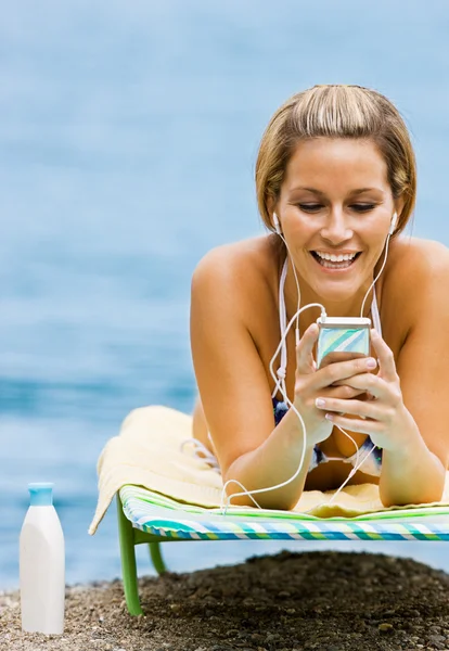 Donna che ascolta mp3 giocatore in spiaggia — Foto Stock