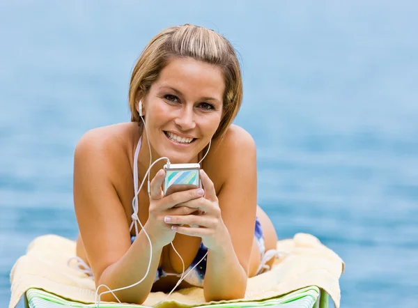 听 mp3 播放器在海滩上的女人 — 图库照片