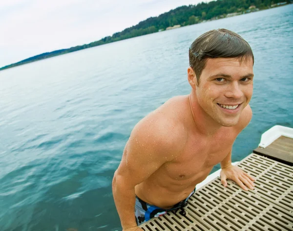 Mann klettert vom See auf Seebrücke — Stockfoto