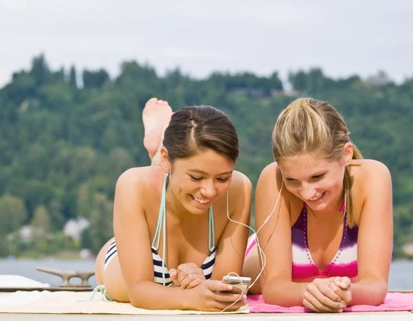 Freunde liegen auf Pier und hören MP3-Player — Stockfoto