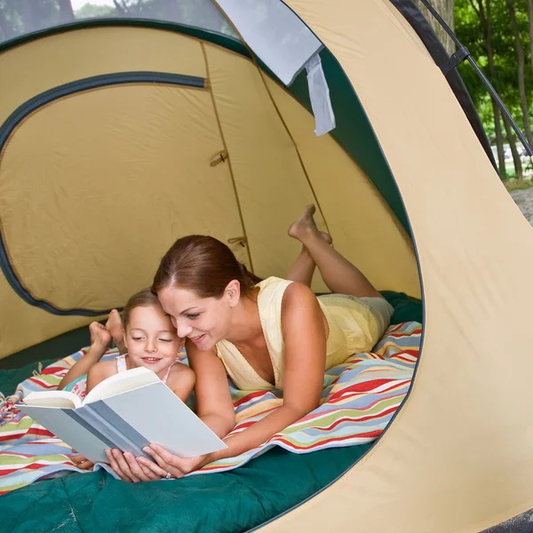 Mother reading to daughter in tent — Stock Photo, Image