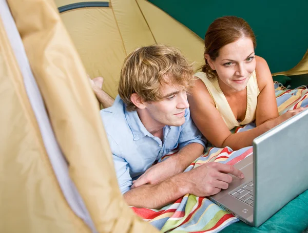 Укладка пары в палатке с помощью ноутбука — стоковое фото