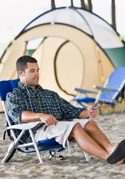 Man using mp3 player at campsite — Stock Photo, Image