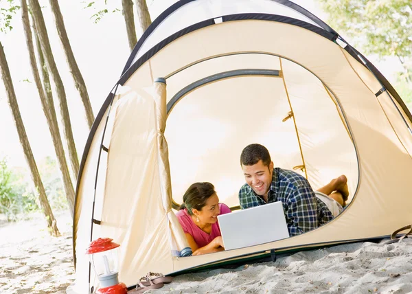 Укладка пары в палатке с помощью ноутбука — стоковое фото