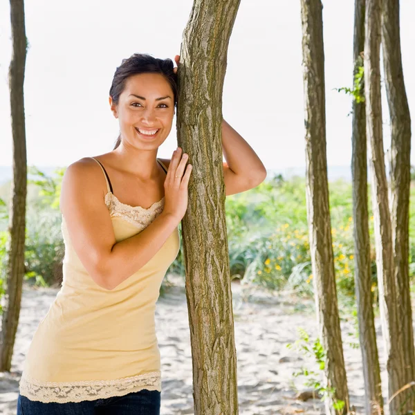 Kobieta, opierając się na drzewo na plaży — Zdjęcie stockowe