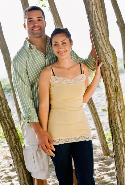 Pareja apoyada en árbol en la playa — Foto de Stock