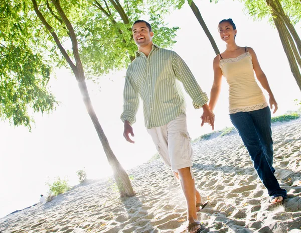 Par promenader hålla händerna på stranden — Stockfoto