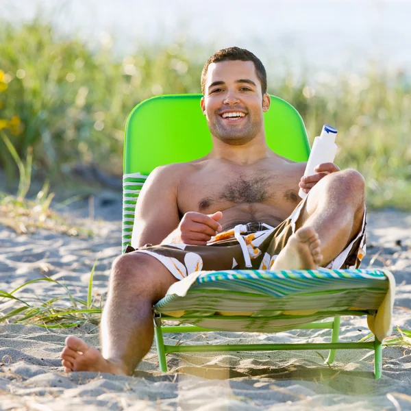 Man applying sunscreen lotion at beach — Stock Photo, Image