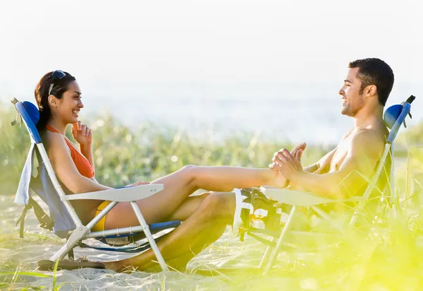 Boyfriend giving girlfriend foot massage at beach — Zdjęcie stockowe