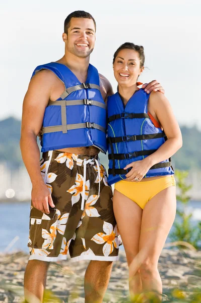 Couple wearing life jackets at beach — Stock Photo, Image