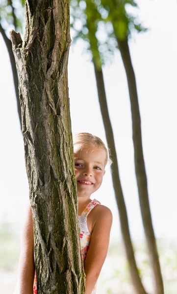 Girl hiding behind tree Stock Photo