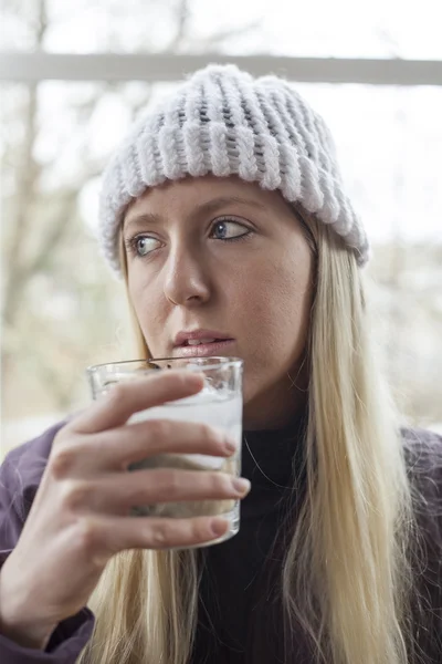 Mujer joven en blanco Stocking Cap agua potable — Foto de Stock
