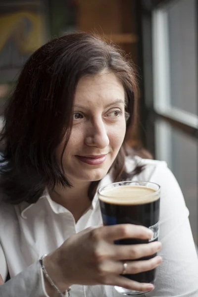 Mladá žena s krásné hnědé oči pít pivo stout — Stock fotografie