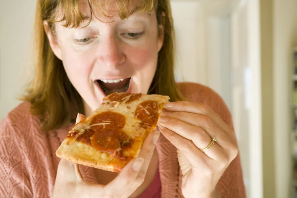 Vrouw pepperoni pizza eten — Stockfoto