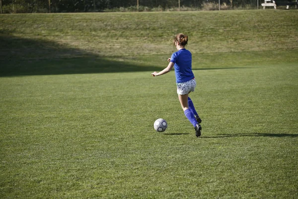 Chica regateando una pelota de fútbol antes de un partido — Foto de Stock