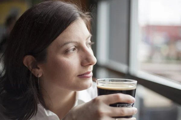 Ung kvinna med vackra bruna ögon som dricker en halvliter stout — Stockfoto