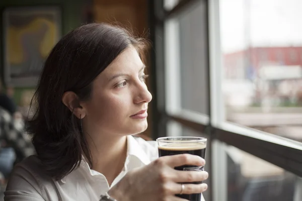 Молодая женщина с красивыми карими глазами пьет пинту портного — стоковое фото