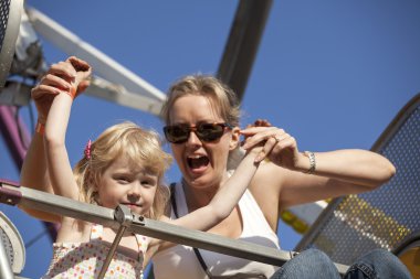 Mother and Daughter on a Ride at the Amusement Park clipart