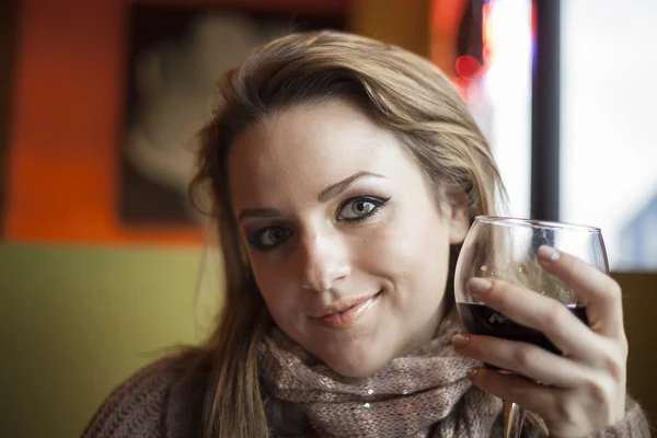 Mulher jovem com belos olhos azuis bebendo vinho tinto — Fotografia de Stock