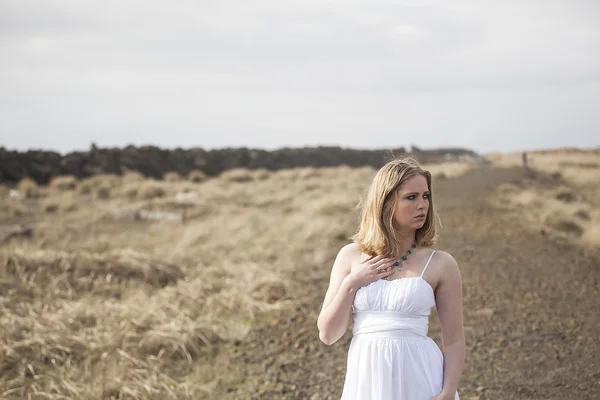Mooie jonge blonde vrouw op strand met witte jurk — Stockfoto