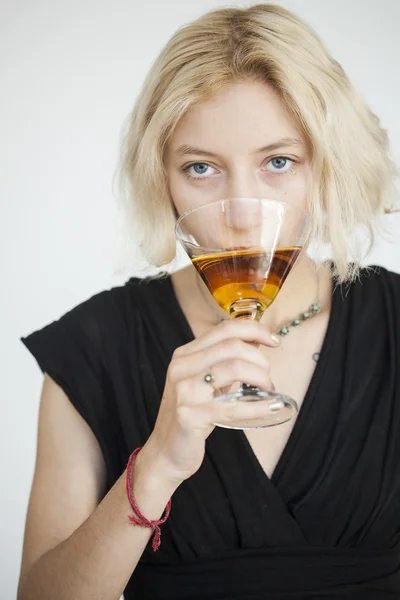 Ξανθιά νεαρή γυναίκα με όμορφα γαλάζια μάτια πίνει ένα μαρτίνι — Φωτογραφία Αρχείου