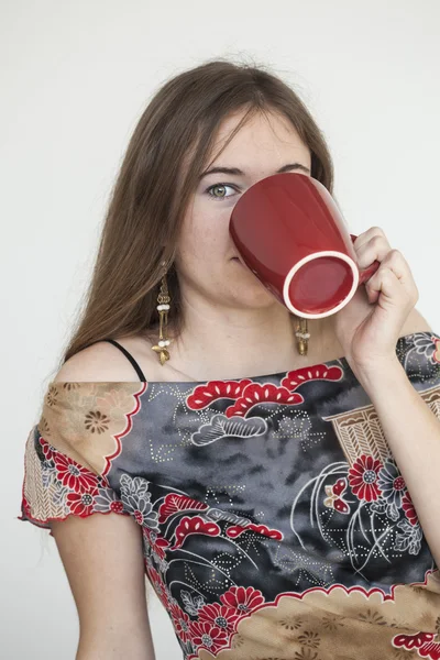 Молодая женщина с красивыми зелеными глазами с красной чашкой кофе — стоковое фото