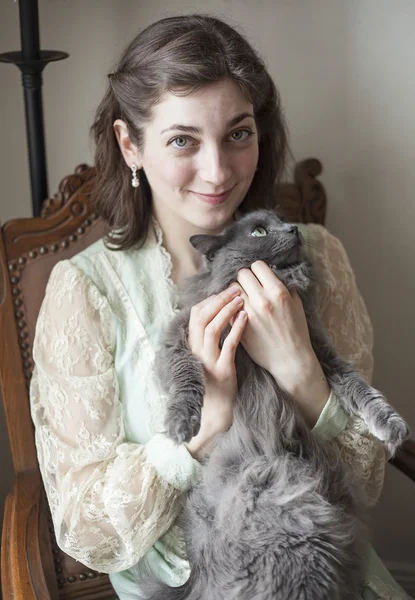 Mujer joven en vestido antiguo sosteniendo su gato gris —  Fotos de Stock