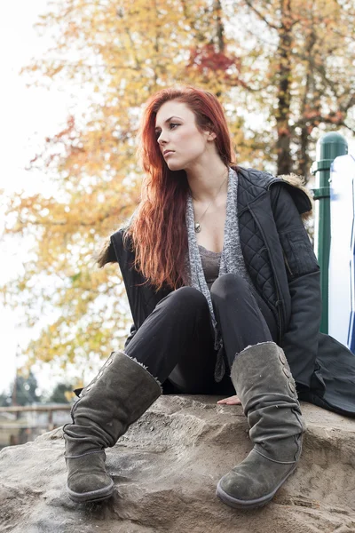 Mujer joven con hermoso cabello Auburn posado en una roca — Foto de Stock