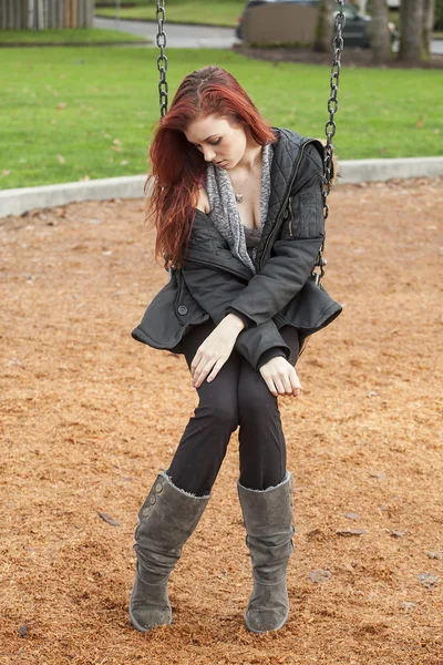 ぶらんこを美しい赤褐色の髪と非常に不幸な若い女性 — ストック写真