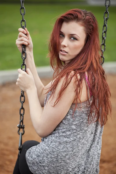 Ung kvinna med vackert rödbrunt hår på en gunga — Stockfoto