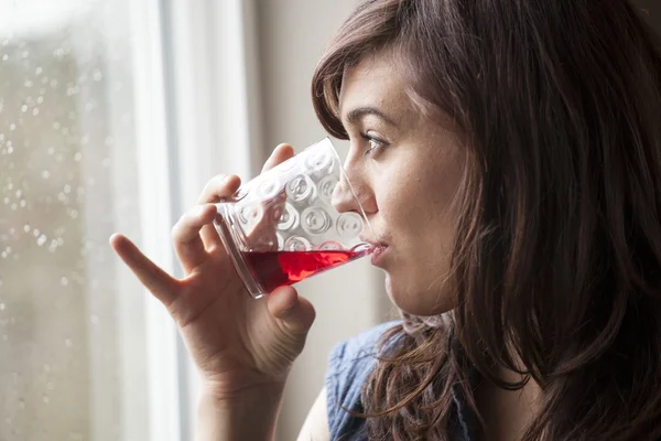 Schöne junge Frau trinkt ein Glas Preiselbeersaft — Stockfoto
