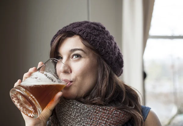 Piękna młoda kobieta w kapelusz i szalik dziany pije piwo — Zdjęcie stockowe