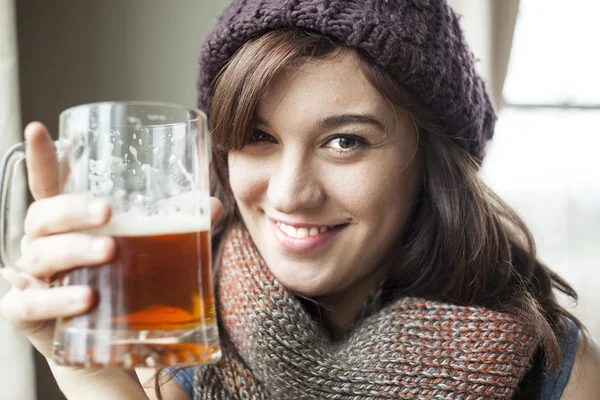 Bella giovane donna in maglia sciarpa e cappello beve birra — Foto Stock