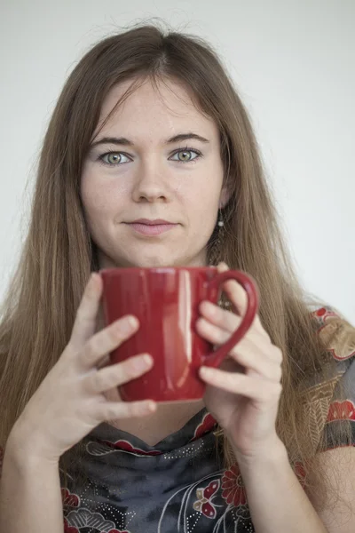 Mujer joven con hermosos ojos verdes con taza de café rojo —  Fotos de Stock