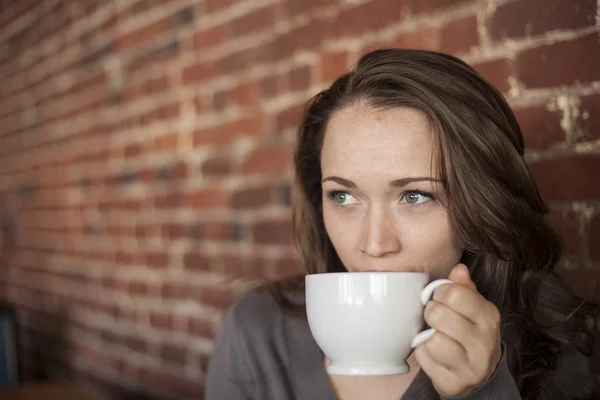 白いコーヒー カップと美しい緑色の瞳を持つ若い女 — ストック写真