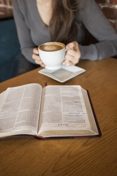 Junge Frau mit weißer Kaffeetasse liest ihre Bibel — Stockfoto