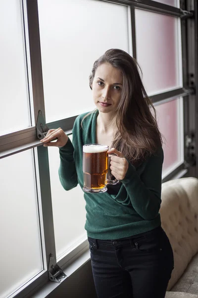 Hermosa mujer joven sosteniendo taza de cerveza — Foto de Stock