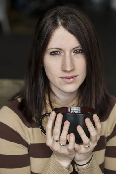 Vacker ung kvinna med brunt hår och ögon håller svart cof — Stockfoto