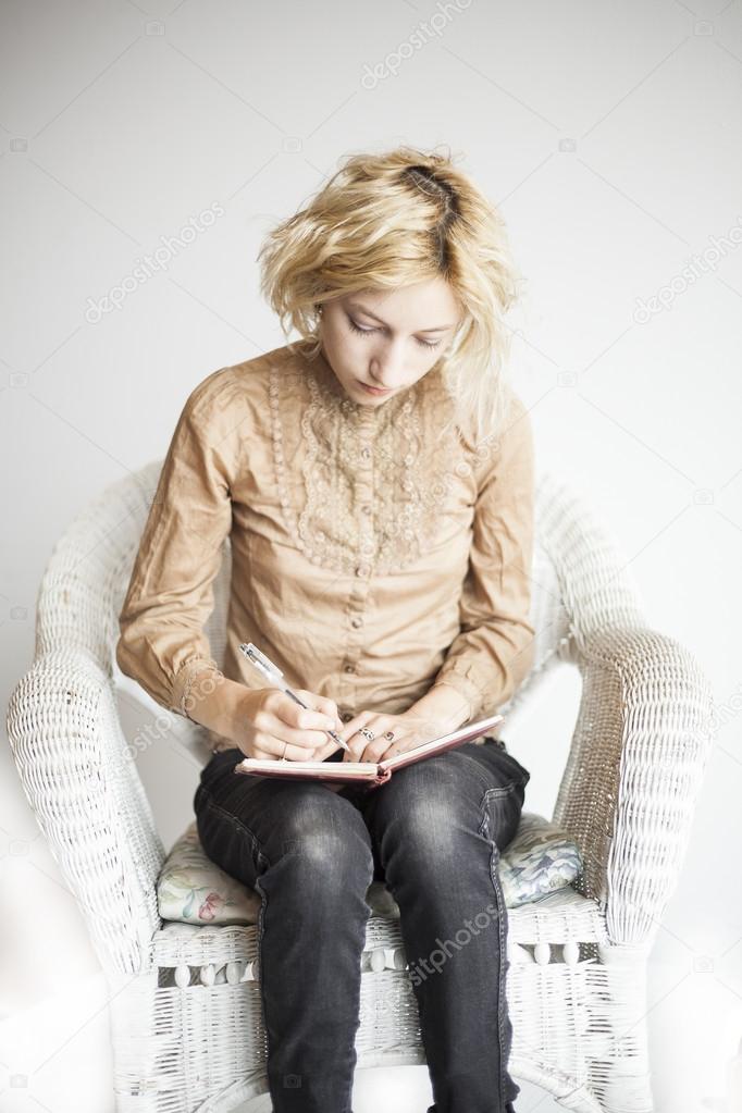 Blonde Young Woman with Beautiful Blue Eyes Writing in Her Journ
