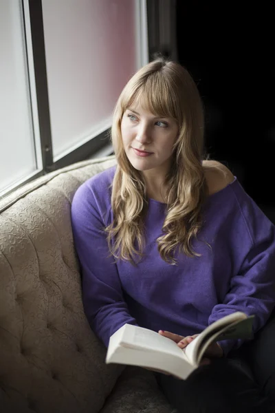 Ung kvinna med vackra blå ögon läser en bok Stockbild