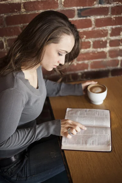 Junge Frau mit weißer Kaffeetasse liest ihre Bibel — Stockfoto