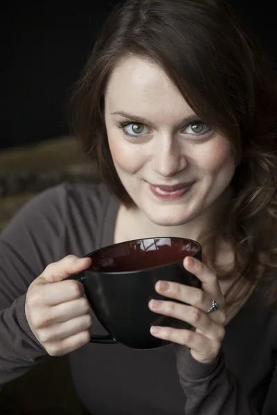 Jeune femme avec de beaux yeux verts et tasse de café noir — Photo