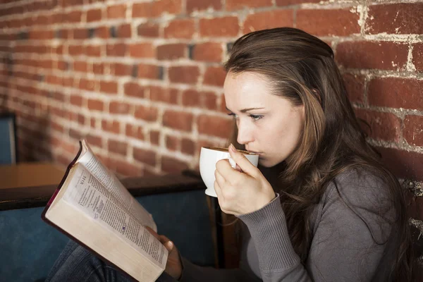 Giovane donna con tazza di caffè bianco legge la sua Bibbia — Foto Stock
