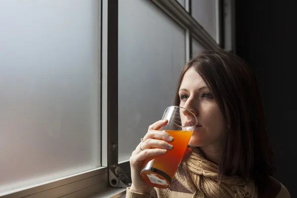 Krásná mladá žena s hnědými vlasy, nápojové sklo mango ju — Stock fotografie