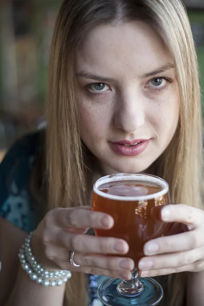 Ξανθιά γυναίκα με όμορφα γαλάζια μάτια πίνει ένα Κύπελλο της μπύρας — Φωτογραφία Αρχείου