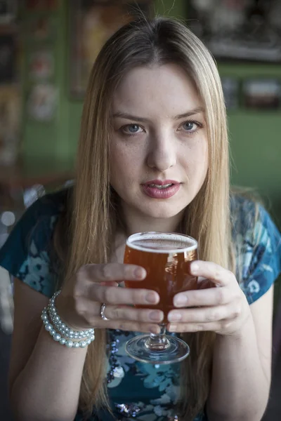 Donna bionda con bellissimi occhi azzurri beve un calice di birra — Foto Stock