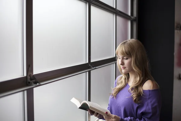 Junge Frau im lila Hemd liest ein Buch — Stockfoto